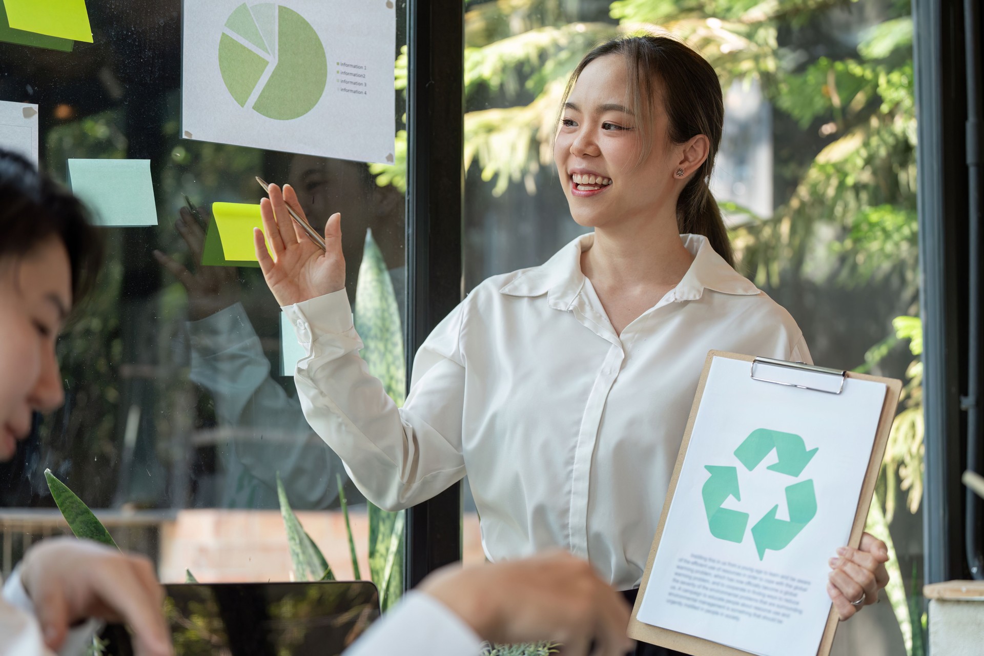 Eco-friendly Initiatives and Engagement. A presenter discussing recycling and sustainability goals in a professional setting.